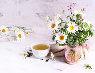 Canvas Print - cup of herbal tea and a bouquet of chamomile flowers