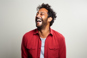 Wall Mural - Portrait of a happy indian man in his 30s laughing isolated on white background