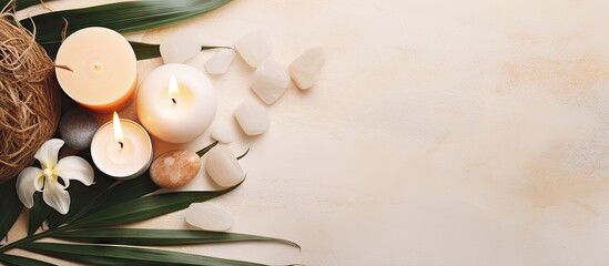 Wall Mural - Flat lay copy space image featuring a soothing spa arrangement consisting of skin care products aromatic stones lit candles and tropical palm leaves on a pastel beige backdrop