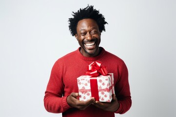 Sticker - Portrait of a smiling afro-american man in his 40s holding a gift while standing against white background