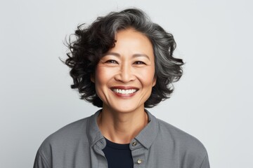 Wall Mural - Portrait of a glad asian woman in her 50s smiling at the camera in white background