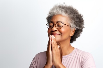 Canvas Print - Portrait of a tender afro-american woman in her 50s joining palms in a gesture of gratitude over white background