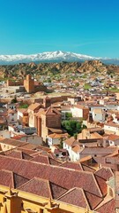 Wall Mural - Aerial view of Guadix old town, province of Granada, Andalusia, Spain. Historic Cathedral building, Alcazaba de Guadix fortress and snow capped Sierra Nevada mountain range at background