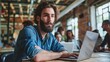 © Антон Сальников - Motivated Caucasian young man with beard working on a laptop in an office. Male Director preparing marketing campaign. Diverse team working on computers.