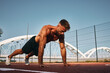 © djile - Shirtless handsome man doing push-ups on the basketball court outside