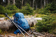 Backpack with tripod and hiking pole during trekking in forest. Outdoor equipment for hike and trekking activity
