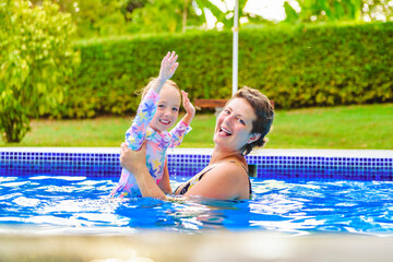 Wall Mural - mother with little girl in pool on sunny day.