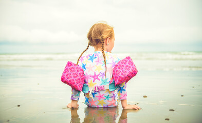 Wall Mural - child girl of 4 years sit on beach of Costa Rica view from back