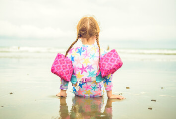 Wall Mural - child girl of 4 years sit on beach of Costa Rica view from back