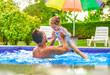 father with little girl in pool on sunny day.