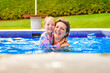 mother with little girl in pool on sunny day.