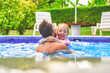 father with little girl in pool on sunny day.