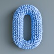 © Ailee Tian - A knitted number 0 in blue color on the gray background.