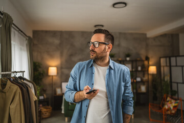 Wall Mural - Portrait of adult man stand and hold mobile phone text message at home