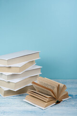 Canvas Print - Book stacking. Open book, hardback books on wooden table and blue background. Back to school. Copy space for text.