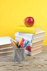 Wall Mural - Books stacking. Books on wooden table and yellow background. Back to school. Copy space for ad text.