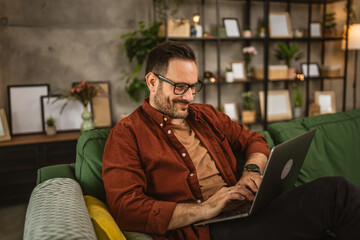 Wall Mural - Adult caucasian man sit at home and look, read on laptop at home