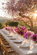 A beautifully decorated outdoor table with bouquets of various flowers, cendles, luxury tableware and cutlery