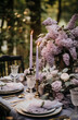 A beautifully decorated outdoor table with bouquets of lilac, candles, luxury tableware and cutlery