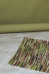 Wall Mural - A green and brown rug with a pattern of stripes sits on a grey floor. The rug is placed in front of a green wall