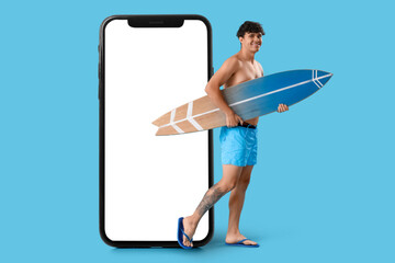 Wall Mural - Young man with surfboard on blue background