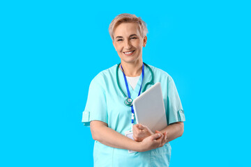 Canvas Print - Mature female nurse with laptop on blue background