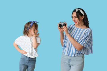 Poster - Beautiful pin-up woman with photo camera and her daughter on blue background