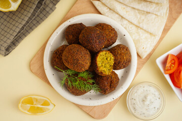 Wall Mural - Plate with delicious falafel balls, tomatoes, sauce and pita on beige background