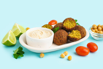 Wall Mural - Plate with delicious falafel balls, hummus, tomatoes and chickpea on blue background