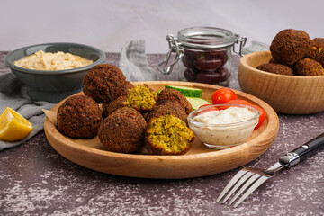 Wall Mural - Wooden plate with delicious falafel balls, sauce and tomatoes on grunge background, closeup