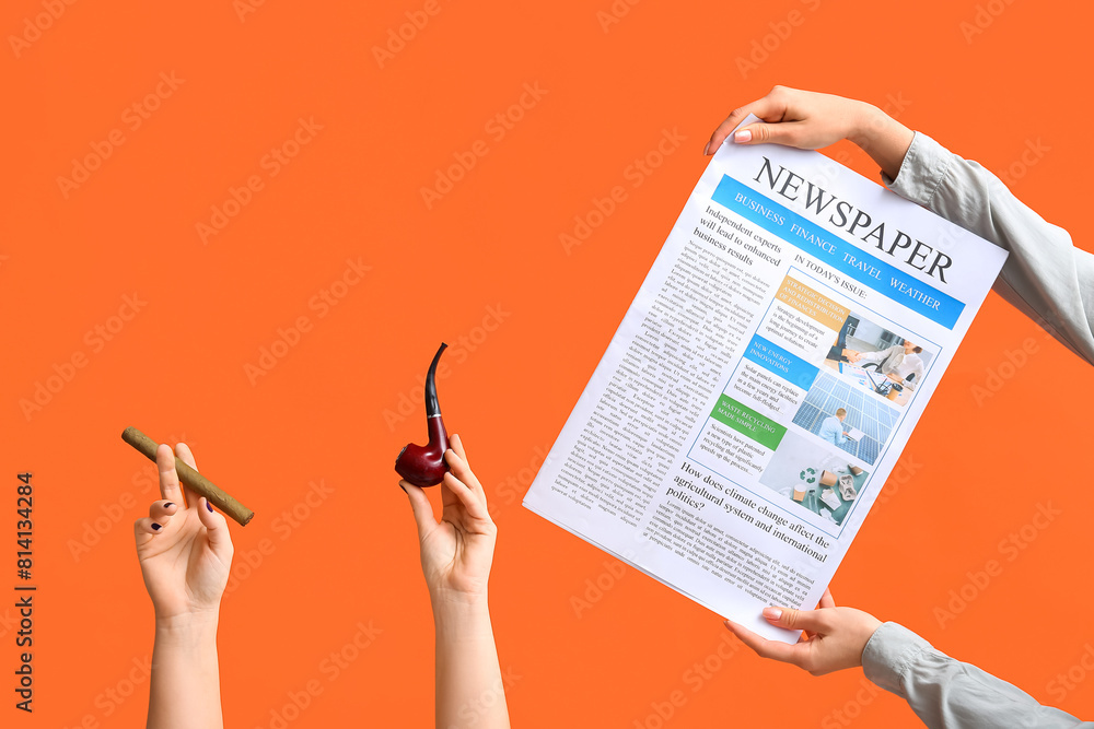 Female hands with newspaper, cigar and smoking pipe on orange background