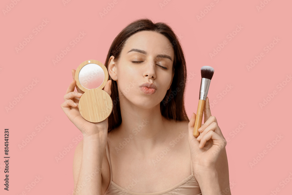 Thoughtful young woman with brush and highlighter on pink background