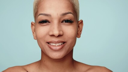 close-up of a cheerful hispanic woman with short hair displaying happiness and beauty against a blue