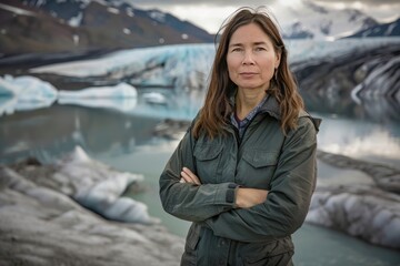 Wall Mural - A woman stands in front of a body of water, wearing a green jacket