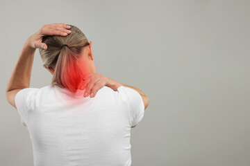 Wall Mural - Woman suffering from neck pain on grey background, back view