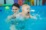 Fototapeta Łazienka - Swimming pool for babies. A baby learns to swim with a coach