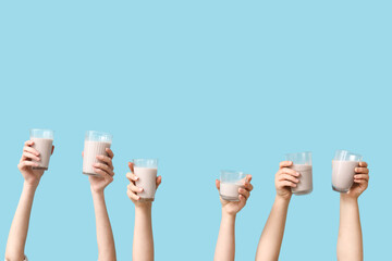 Wall Mural - Female hands with glasses of sweet chocolate milk on blue background