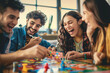 © AndyGordon - Friends gathered around a table playing board games, laughing as they compete and enjoy each other's company