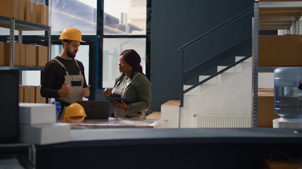 Wall Mural - Dolly out shot of employees doing warehouse inventory analysis, keeping quality standards high. Experts in storage room checking labels on stockpiled merchandise, crosschecking delivery info