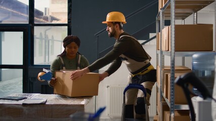 Wall Mural - Dolly in shot of manager in warehouse supervising trainee sealing cardboard box packages. Storage building personnel properly securing goods to avoid hazards during shipping