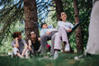 © qunica.com - A serene scene of four friends sitting under tree shades in a park, enjoying a peaceful day with whispers of nature around.