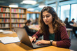 © fahrwasser - A female student using a laptop and taking notes during an online class