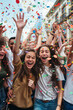 © fahrwasser - Young woman exudes happiness amidst colorful confetti at a vibrant celebration