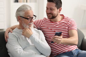 Poster - Happy son and his dad watching something on smartphone at home