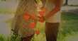 Image of heart icons over caucasian couple holding hands