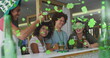 Image of clover icons over diverse friends drinking beer