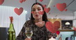 Image of hearts over caucasian woman drinking wine and having image call