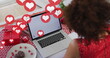 Image of heart icons over african american woman using laptop with copy space, slow motion
