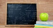 Image of stack of books and apple over mathematical equations and formulae