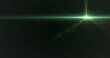 Green light beam crossing dark background, creating lens flare